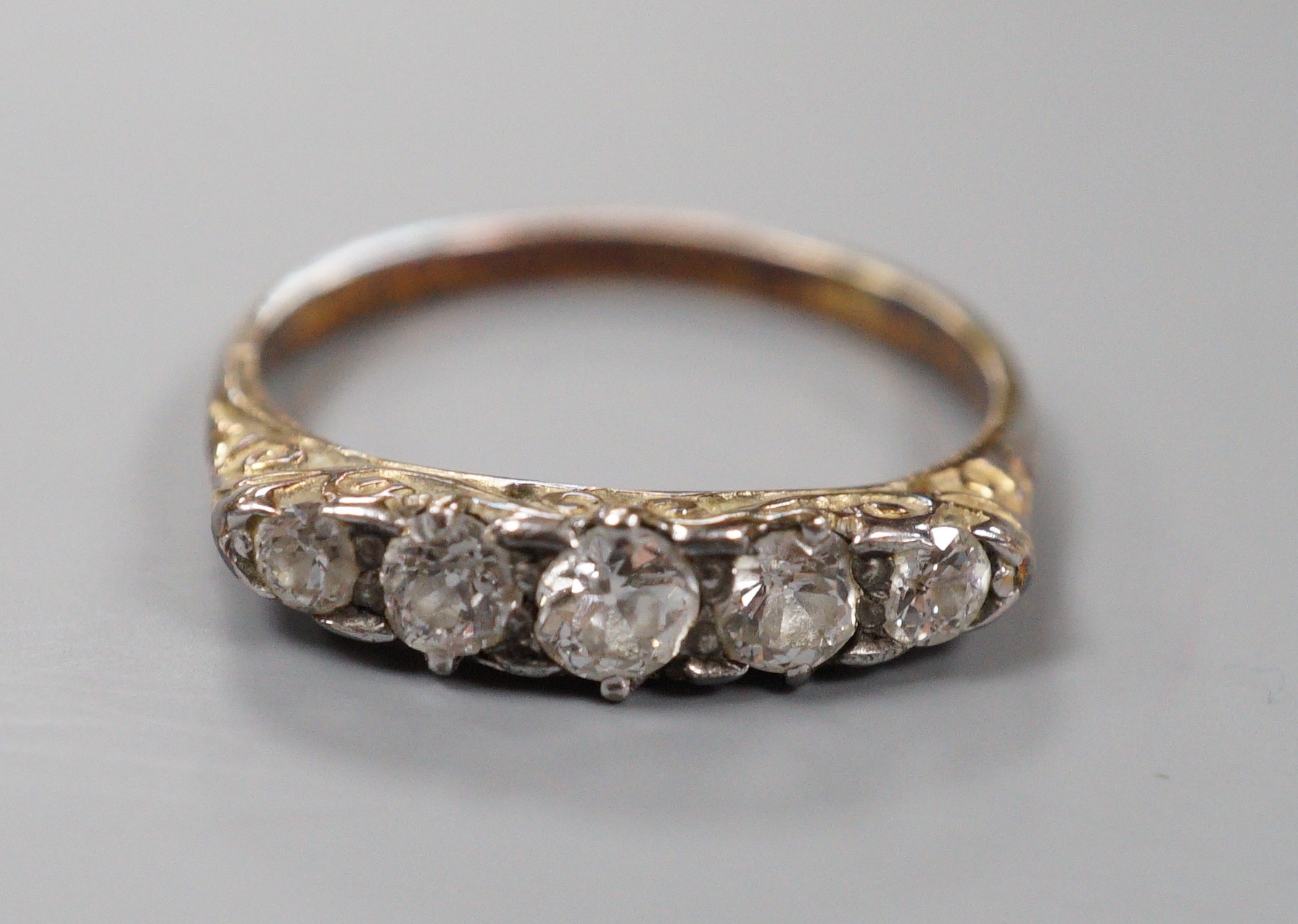 An early 20th century 18ct and graduated five stone diamond set half hoop ring, size P/Q, gross weight 2.7 grams.